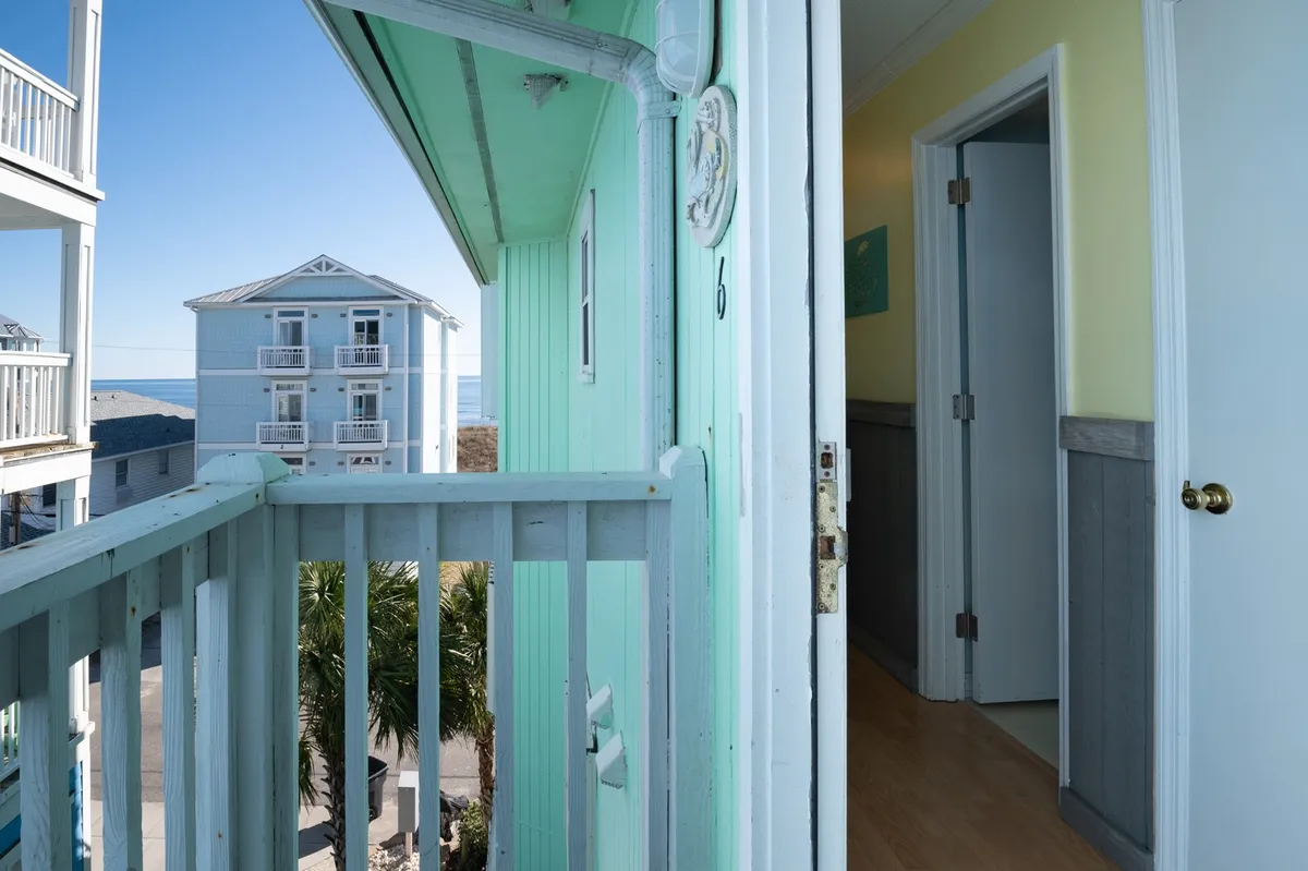 A tranquil exterior view from a private balcony with a railing overlooking the ocean and swaying palm trees. The setting is perfect for relaxation after a day of adventure, with serene ocean vistas and a sense of privacy.