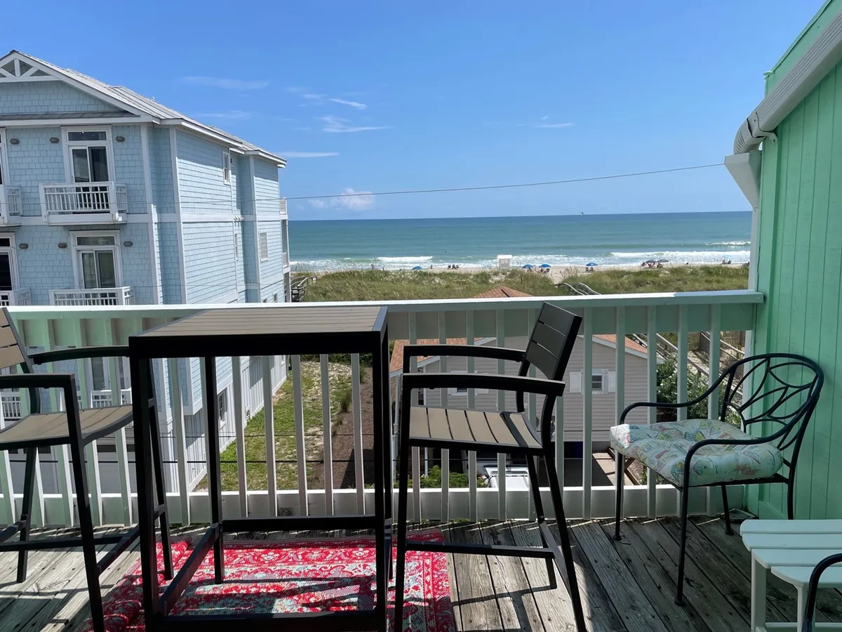 An inviting outdoor deck with comfortable seating positioned to enjoy panoramic ocean views. The area features a cozy rug and space for drinks or snacks, making it ideal for morning coffee, sunset cocktails, or gatherings with friends—all with the sound and sight of the ocean as a backdrop.